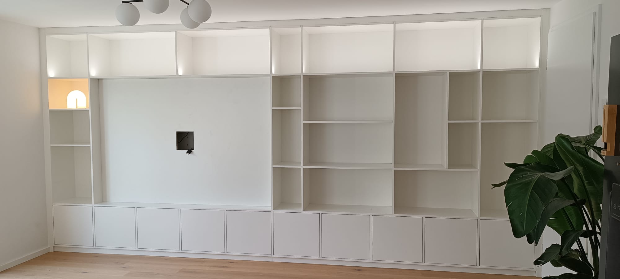 Wohnwand mit Türen, offenen Regalen und Platz für den Fernseher: Beispiel für einen Einbauschrank im Wohnzimmer.
