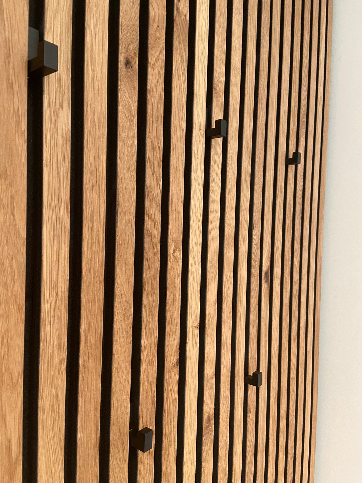 Kleiderhaken zwischen Holzpaneelen hinter der Sitzgelegenheit eines Garderoben-Einbauschranks in München