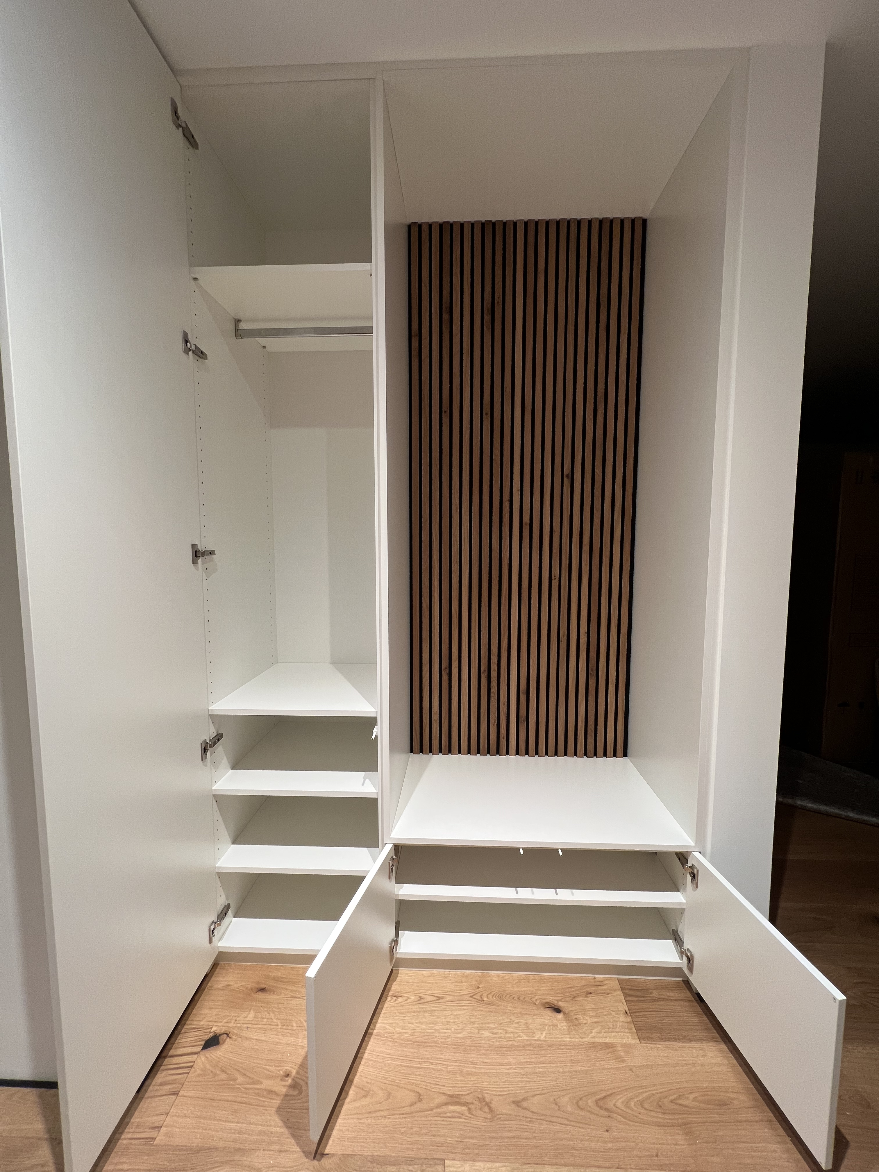 Geöffneter Garderoben-Einbauschrank im Flur, weiß, mit Holzpaneelen und Sitzgelegenheit